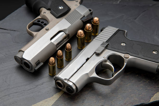 istock Automatic handguns and bullets on black stone background 1329452689