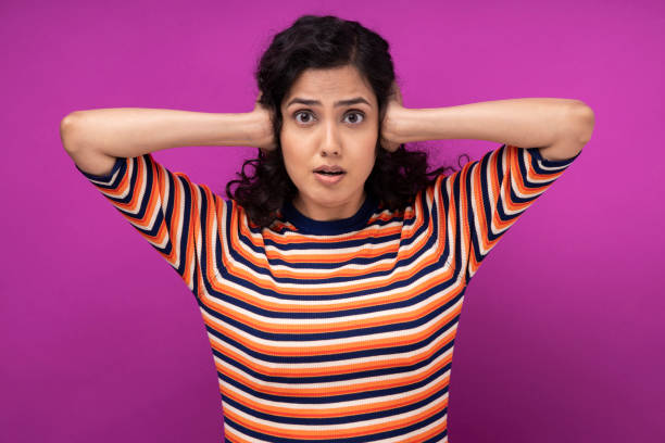 Portrait of young women standing isolated over purple background Adult, Adults Only, India, Indian ethnicity, curly hair, hands covering ears stock pictures, royalty-free photos & images