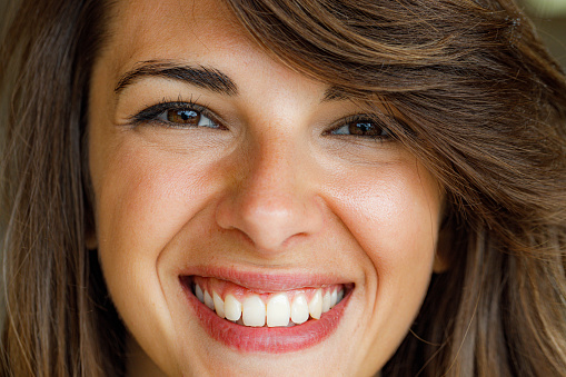 Close up of happy woman with brown eyes looking at camera.