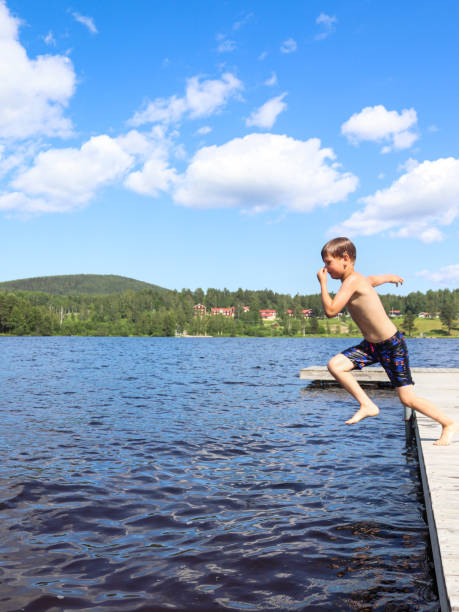 istock Boy is jumping into the water from jetty 1329458992