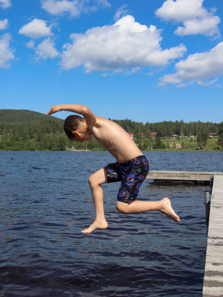 istock Boy is jumping into the water from jetty 1329458995