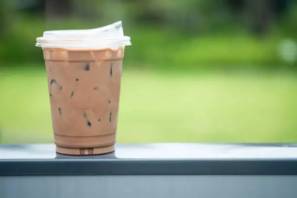 Photo of Iced coffee mocha in plastic glass with new lid design for don't use drink straw. Concept of reduce the use of plastic straw.