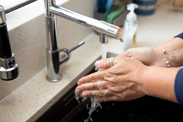 istock Close-up of a woman's hands being washed under running water at a kitchen sink 1329465902
