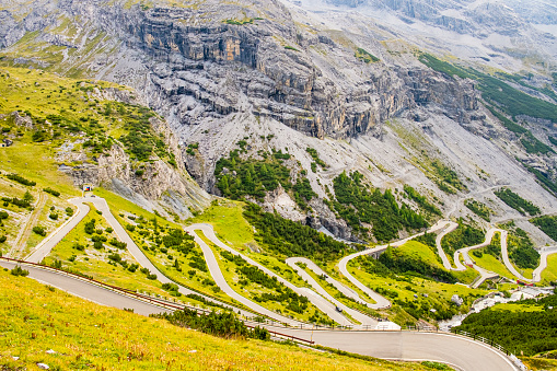 Aerial view of bikers riding on winding road in Dolomites, European Alps.