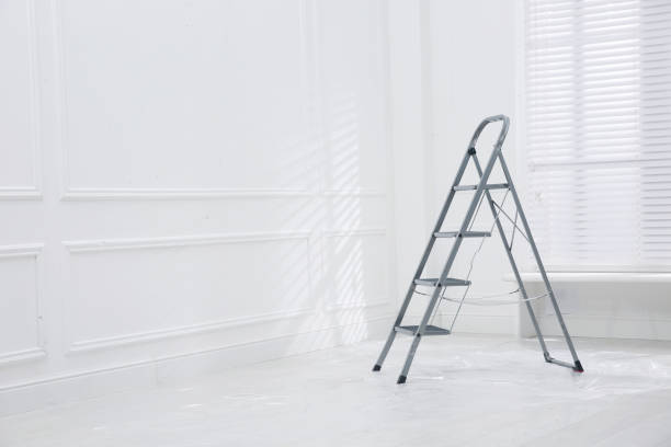 Metal stepladder on floor covered with plastic in empty room, space for text
