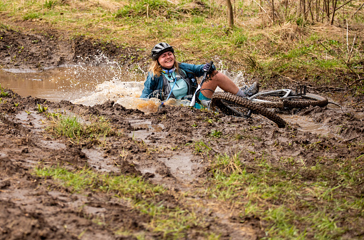 Young woman  falling in a puddle while riding mountain bike