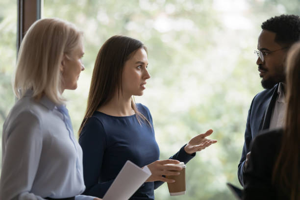 istock Serious young employee talking to diverse coworkers 1329476205