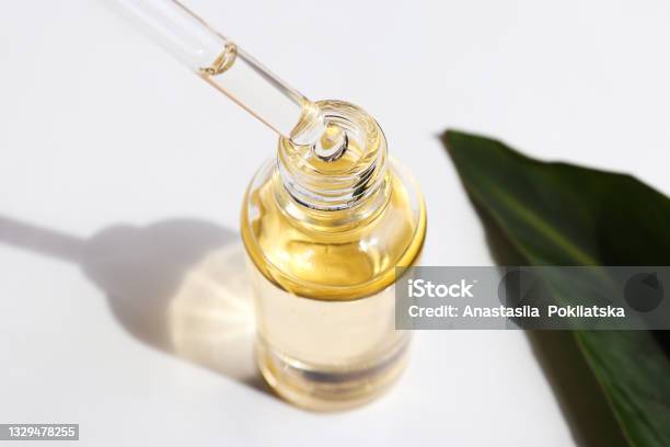 Bottle Of Cosmetic Essential Oil And Green Leaf Serum Oil Is Dripping From Dropper Closeup Beauty And Body Care Concept Serum Skin Care Product Hard Light Stock Photo - Download Image Now