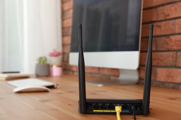 istock Modern wi-fi router near computer on wooden table 1329481200
