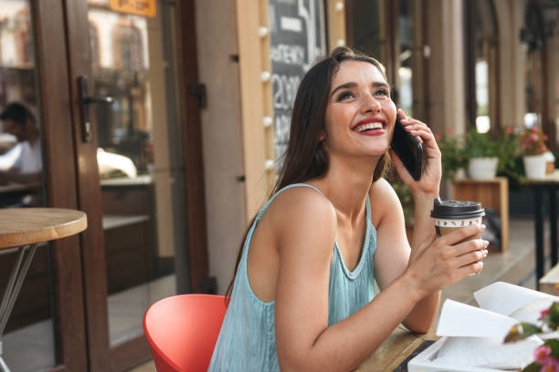 istock Cheerful woman talking by mobile phone drinking coffee. 1329482136