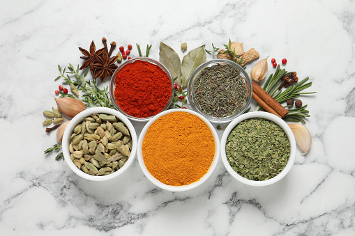 Flat lay composition with different natural spices and herbs on white marble table
