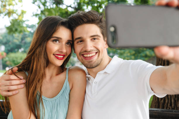 istock Loving couple sitting outdoors while make selfie by mobile phone. 1329484149