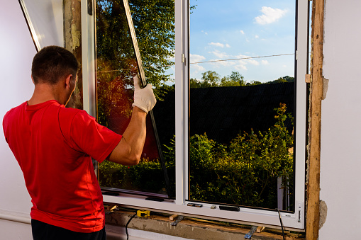 The worker inserts glass into the window frame, triple glazing of the plastic window, insulation and insulation.2020