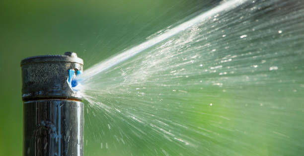 Automatic lawn watering waters the lawn. The rotary nozzle of the self-watering system sprays water on grass and plants. Maintaining the right level of humidity in the garden.