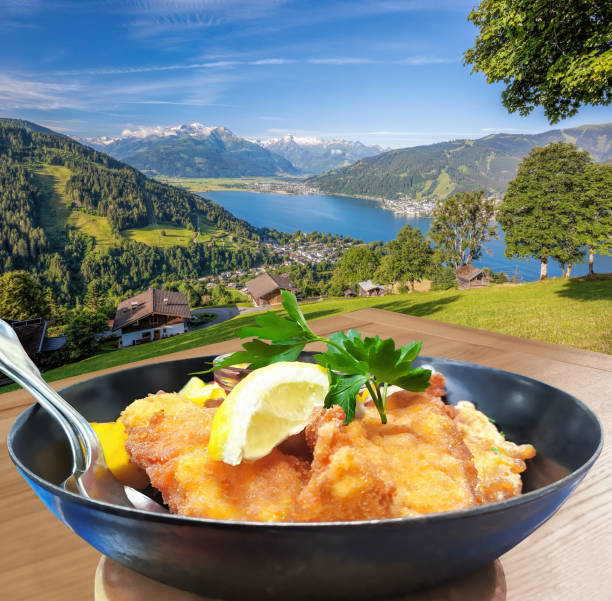 Traditional austrian food (Vinner schnitzel) against Zell am see village with lake in Austria Traditional austrian food (Vinner schnitzel) against Zell am see village with lake in Austria vinner stock pictures, royalty-free photos & images