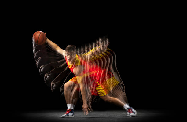 ein junger basketballspieler trainiert mit ballisoliertem hintergrund auf dunklem hintergrund mit stroboskopeffekt. konzept des profisports, hobby. - stroboscopic image stock-fotos und bilder