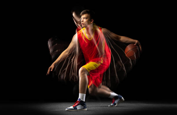istock One young basketball player training with ball isolated on dark background with stroboscope effect. Concept of professional sport, hobby. 1329486674