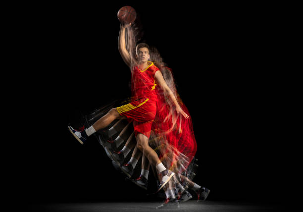 istock One young basketball player training with ball isolated on dark background with stroboscope effect. Concept of professional sport, hobby. 1329486719
