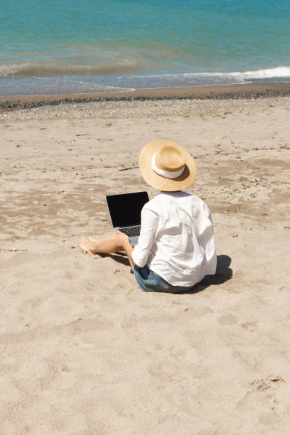 istock Young woman using laptop computer on a beach. Vacation lifestyle communication. Freelance work concept 1329488090