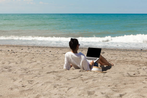 istock Young woman using laptop computer on a beach. Vacation lifestyle communication. Freelance work concept 1329488099