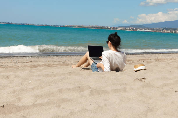 istock Young woman using laptop computer on a beach. Vacation lifestyle communication. Freelance work concept 1329488103