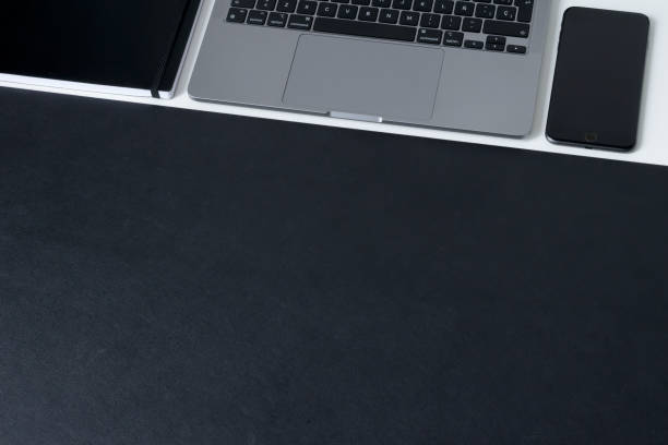 istock Clean modern workspace with laptop, notebook and matte black work surface on white desk 1329492784