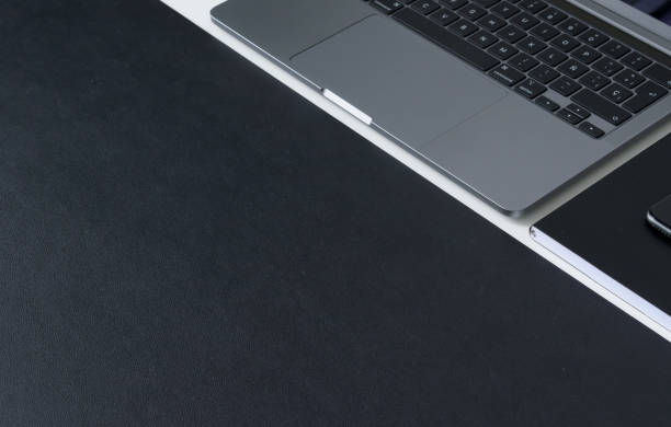 istock Clean modern workspace with laptop, notebook and matte black work surface on white desk 1329492936