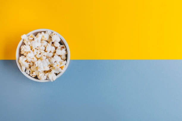 istock White bowl with popcorn on blue and yellow background. 1329493169
