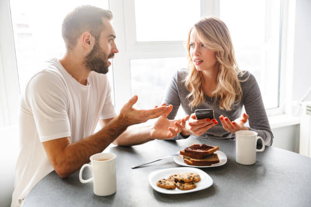 istock Loving couple sitting at the kitchen have a breakfast using mobile phone. 1329495801