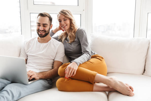 istock Amazing loving couple sitting indoors at home using laptop computer. 1329495901