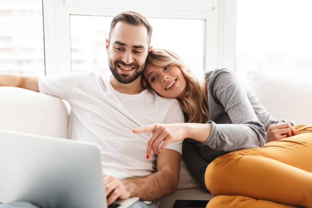 istock Amazing loving couple sitting indoors at home using laptop computer. 1329495916