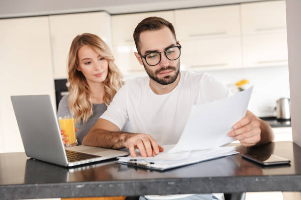 istock Young loving couple sitting at the kitchen using laptop computer. 1329495982