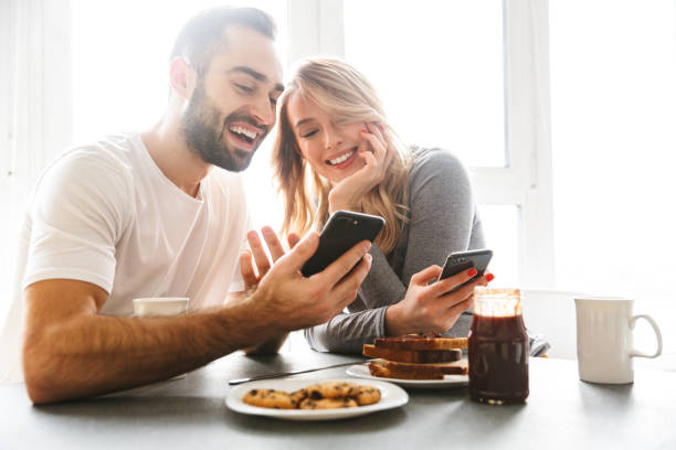 istock Loving couple sitting at the kitchen have a breakfast using mobile phones. 1329495991
