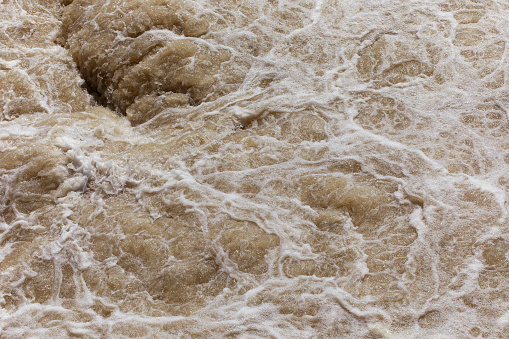 Water foam texture, rough water on the river, natural background, flood, power in nature concept.