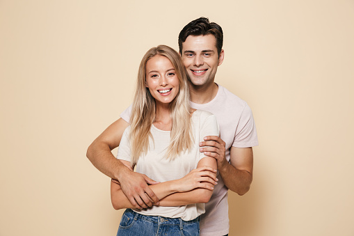 A cropped studio portrait of a dapper young man with a beautiful girl on his arm