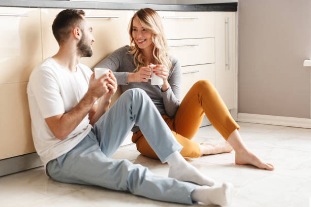 Amazing young loving couple sitting at the kitchen drinking tea on a floor.