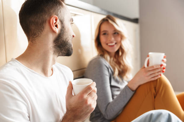 Amazing young loving couple sitting at the kitchen drinking tea on a floor.