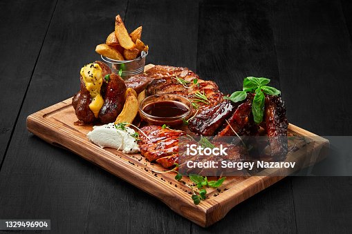istock Grilled assorted meat platter with potato wedges and sauces 1329496904