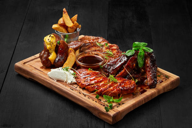 grilled assorted meat platter with potato wedges and sauces - bandeja imagens e fotografias de stock