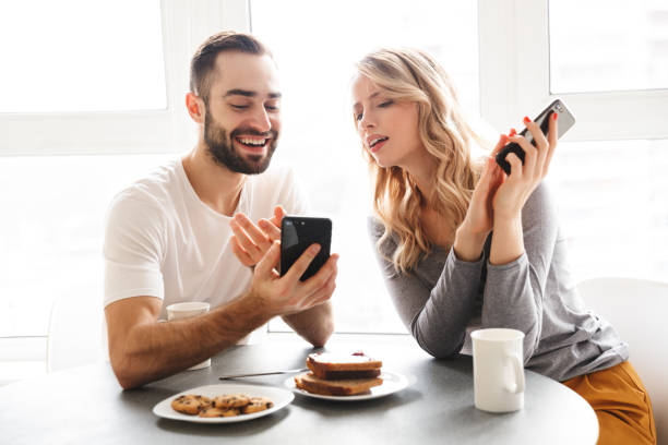 istock Loving couple sitting at the kitchen have a breakfast using mobile phones. 1329497128
