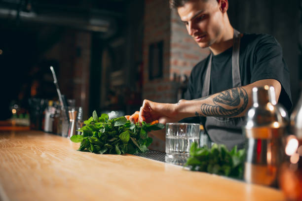 istock One young professional bartender in cafe or restaurant preparing fresh cocktails, drinks standing behind a long wooden bar. 1329498230