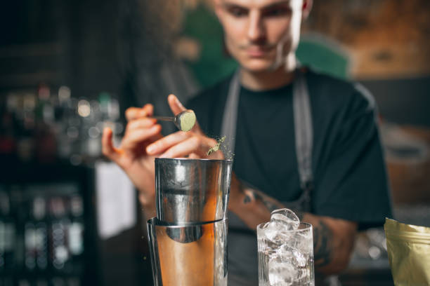 istock Young caucasian guy, professional bartender in apron mixing cocktails in pub or cafe. 1329498241