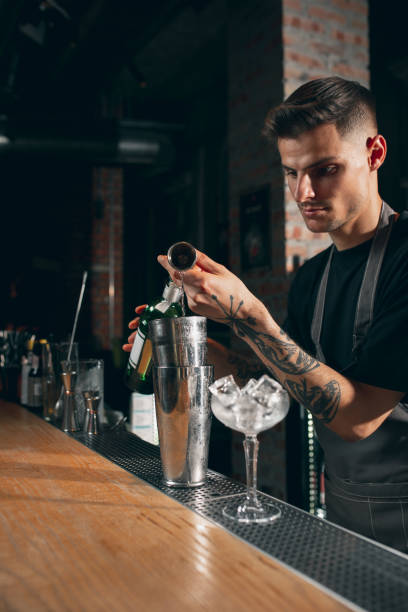 istock One young handsome bartender preparing an alcohol drink in cocktail shaker standing behind bar counter 1329498246