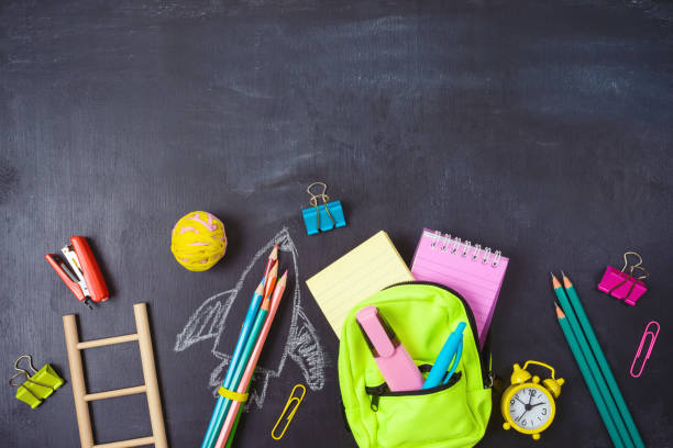 istock Back to school background with bag backpack, rocket sketch and school supplies over chalkboard 1329500551