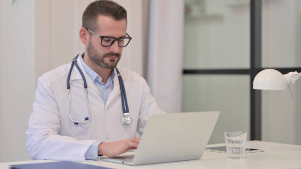 istock Middle Aged Doctor Working on Laptop in Hospital 1329501182