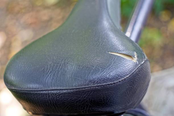 one black bike seat with ripped leather on bicycle