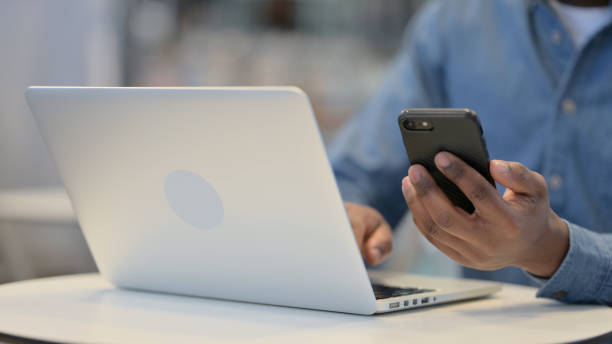 istock Man Working on Smartphone and Laptop, Close Up 1329501975