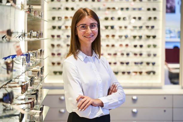 istock Cheerful young woman in glasses standing in optical store 1329502017