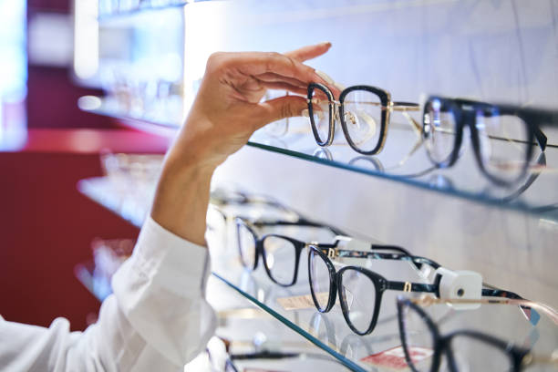 istock Female hand taking eyeglasses from shelf in optical store 1329502052