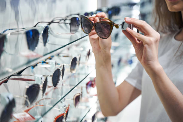 istock Young woman choosing sunglasses in optical store 1329502072